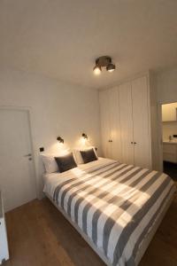 a bedroom with a large bed with striped sheets at The White Boutique Loft in Antwerp