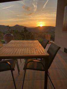 a wooden table and chairs on a patio with the sunset at Masia La Sort in Riba-roja d'Ebre