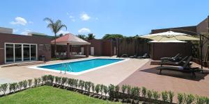 a swimming pool with two chairs and an umbrella at Candlewood Suites - Celaya by IHG in Celaya