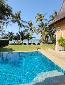 a swimming pool in front of a house with palm trees at Beachfront Pool Villa in Ko Chang +25 photos