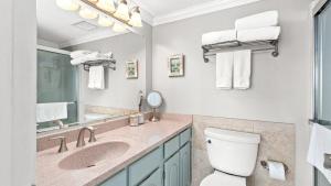a bathroom with a toilet and a sink and a mirror at Beachfront Breeze by AvantStay in Panama City Beach +27 photos