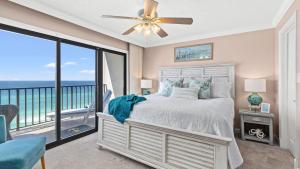 a bedroom with a bed and a balcony with the ocean at Beachfront Breeze by AvantStay in Panama City Beach
