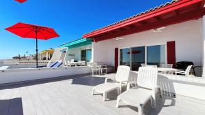 a patio with white chairs and a table and an umbrella at Charming & Cozy Beachfront Condo Las Olas I 19 in Puerto Peñasco
