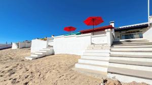a building with red umbrellas on the beach at Charming & Cozy Beachfront Condo Las Olas I 19 in Puerto Peñasco +18 photos
