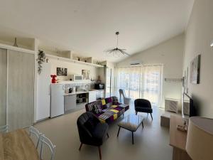 a living room with a couch and chairs and a kitchen at Maison au calme proche accès rocade in Montauban