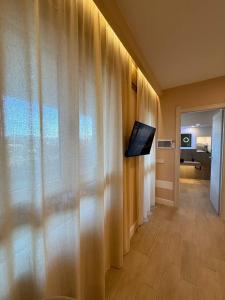a living room with a curtain and a tv on a wall at Windofsand Room in Cagliari