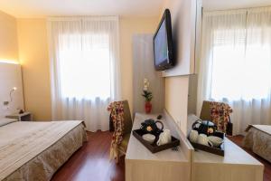 ein Hotelzimmer mit einem Bett und einem Flachbild-TV in der Unterkunft Primavera in Stresa