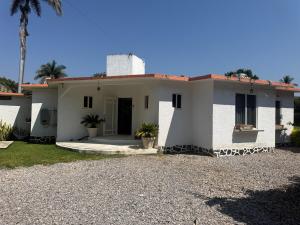 a white house with a palm tree in front of it at Casa Los Cardenales Ticuman in Ticumán
