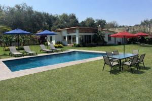 a pool with chairs and tables and umbrellas at Casa Los Cardenales Ticuman in Ticumán