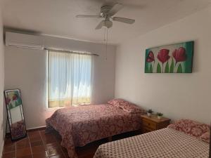 a bedroom with two beds and a window with flowers at Casa Los Cardenales Ticuman in Ticumán +18 photos