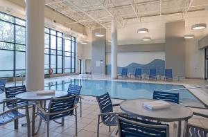 a pool with tables and chairs in a building at DoubleTree by Hilton West Edmonton in Edmonton