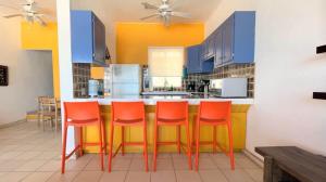 a kitchen with orange chairs at a kitchen counter at Cozy & Colorful Beachfront Condo Las Olas II 4 in Puerto Peñasco