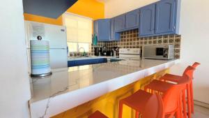 a kitchen with blue cabinets and orange stools at Cozy & Colorful Beachfront Condo Las Olas II 4 in Puerto Peñasco