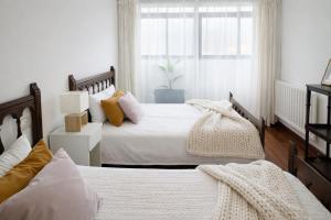 a bedroom with two beds and a window at Holibai Amieiro Apto amplio y luminoso cerca de la playa, Baiona in Baiona +5 photos