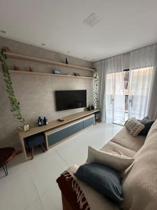 a living room with a couch and a flat screen tv at Casa da Alê in Camaçari