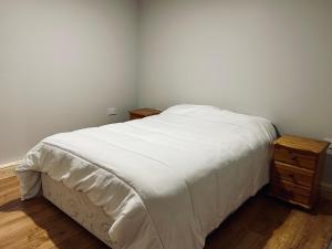 a bedroom with a white bed and a wooden dresser at Ocean view apartment in Tralee