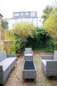 three wicker chairs and a table on a patio at Brighton Colour Pop House- Sleeps up to 12 in Brighton & Hove