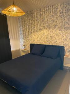 a bedroom with a bed with blue sheets and wallpaper at Gîte la pause en baie in Pendé
