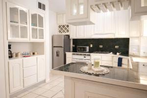 a white kitchen with white cabinets and a refrigerator at Casa Real in Manuel F. Martínez
