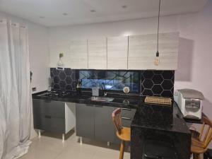 a kitchen with a black counter top and a desk at Casa Telhado Inclinado in Saquarema +20 photos