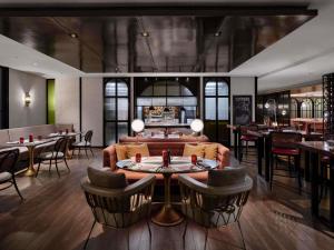 a restaurant with a couch and tables and chairs at Pullman Bandung Grand Central in Bandung