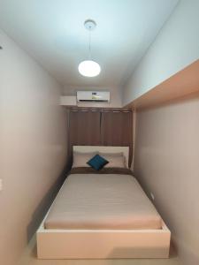 a small bedroom with a bed with a blue pillow at Tahanan in Iloilo City