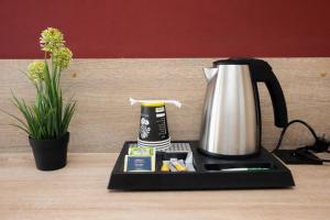 a coffee maker on a tray on a table with a flower at NIVAN Hostel in Hamburg