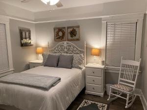 a bedroom with a white bed and a chair at Classic California Bungalow Downtown in Bakersfield