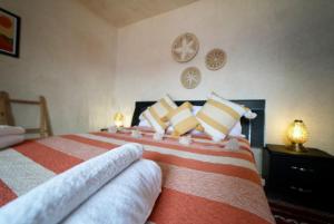 a bedroom with a large bed with orange and white pillows at Riad Medina Charme et Sérénité in Essaouira
