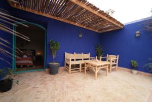 a blue room with a table and chairs and a bed at Riad Medina Charme et Sérénité in Essaouira