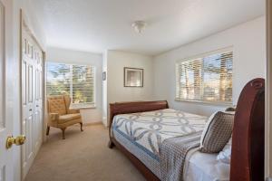 a bedroom with a bed and a chair and two windows at Timber Creek Escape in Sisters