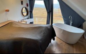 a bedroom with a tub and a bed with a window at Design Villa with Panoramic Views & Large Windows in Miðvágur