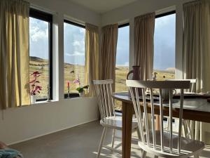 a dining room with a table and chairs and windows at Design Villa with Panoramic Views & Large Windows in Miðvágur