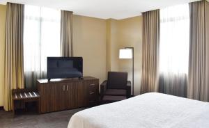 a hotel room with a bed and a tv and a chair at Hampton Inn Tampico Zona Dorada in Tampico