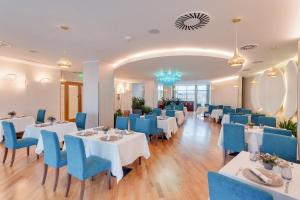 a restaurant with white tables and blue chairs at DoubleTree by Hilton Hotel Cluj - City Plaza in Cluj-Napoca
