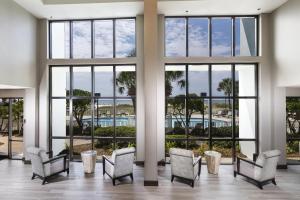 a large lobby with chairs and windows at The Island House Hotel a Doubletree by Hilton in Orange Beach