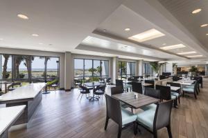 a restaurant with tables and chairs and windows at The Island House Hotel a Doubletree by Hilton in Orange Beach