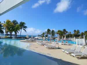 a swimming pool with lounge chairs and the ocean at Ti Coco Vanni Studio Sea View in Belle-Allée