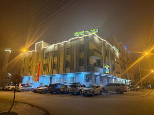 a building with cars parked in a parking lot at night at قولد شير 2 in Salalah