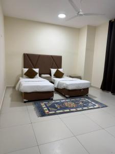a bedroom with two beds and a rug at قولد شير 2 in Salalah