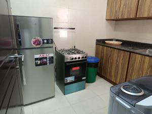 a kitchen with a stove and a refrigerator at قولد شير 2 in Salalah
