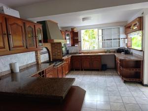 a large kitchen with wooden cabinets and a window at Villa Renée in Petit-Bourg