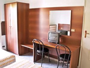 ミラノにあるホテル ラリーのデスク、椅子2脚、テレビが備わる客室です。