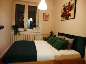 a bedroom with a bed with green pillows and a window at Spacious 3 room apartment in center perfect for family or a group of friends in Warsaw