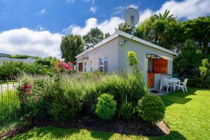 a small white house in a yard with plants at Ria's Rest Self Catering Flatlet in Sedgefield