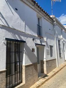 a white building with black barred windows on a street at Moreria Suites in Constantina