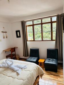 a bedroom with two chairs and a bed and a window at Big Vacation Hostel in Cusco