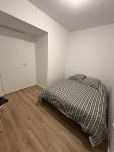a white bedroom with a bed and a wooden floor at LONI EXPERIENCES - L'Escale in Challans