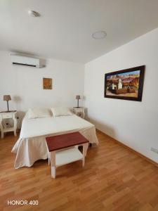 a bedroom with a bed and a painting on the wall at Hostal Virgen del Rosario Cafayate in Cafayate