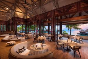a restaurant with tables and chairs and the ocean at Conrad Bora Bora Nui in Bora Bora